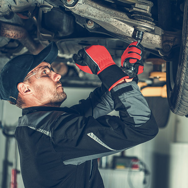 Mechanic fixing vehicle suspension inside shop in the New Port Richey and Port Richey, FL area