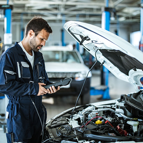 Mechanic checking car's performance with diagnostic tool inside workshop