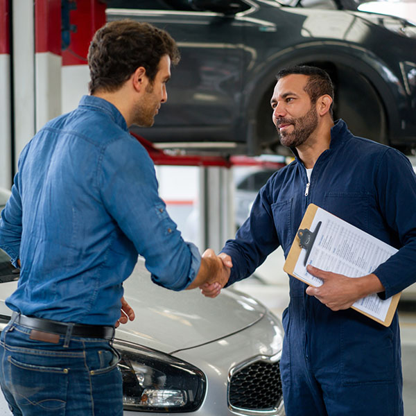 Mechanic greeting customer with handshake inside auto shop