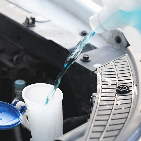 Mechanic filing up windshield washer reservoir