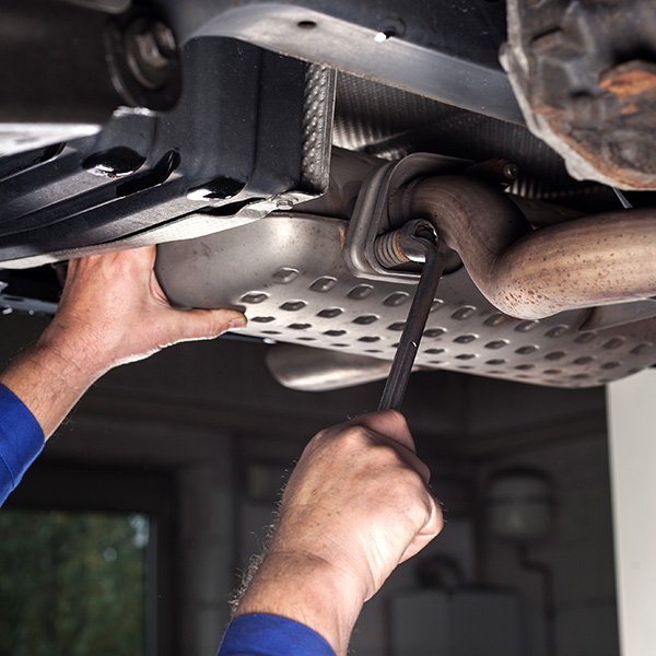 Mechanic fixing car's exhaust system