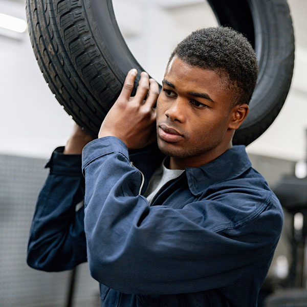 Mechanic carrying a tire inside the garage in the New Port Richey and Port Richey, FL area