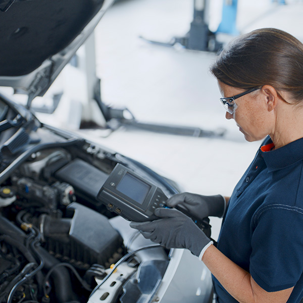 Mechanic inspecting car using device