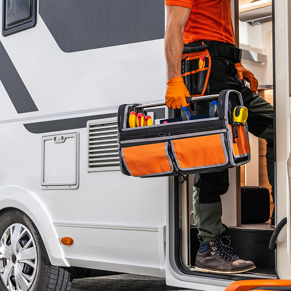 Mechanic holding tool box entering RV car