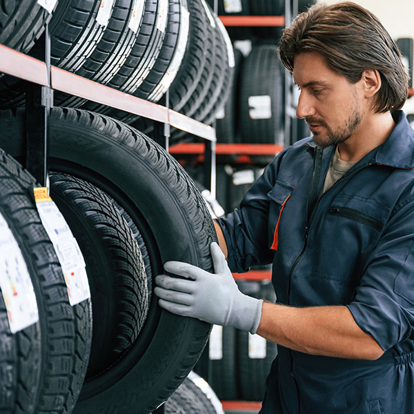 Mechanic grabbing car tire from the storage rack