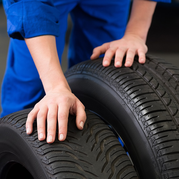 Mechanic holding car tires at garage