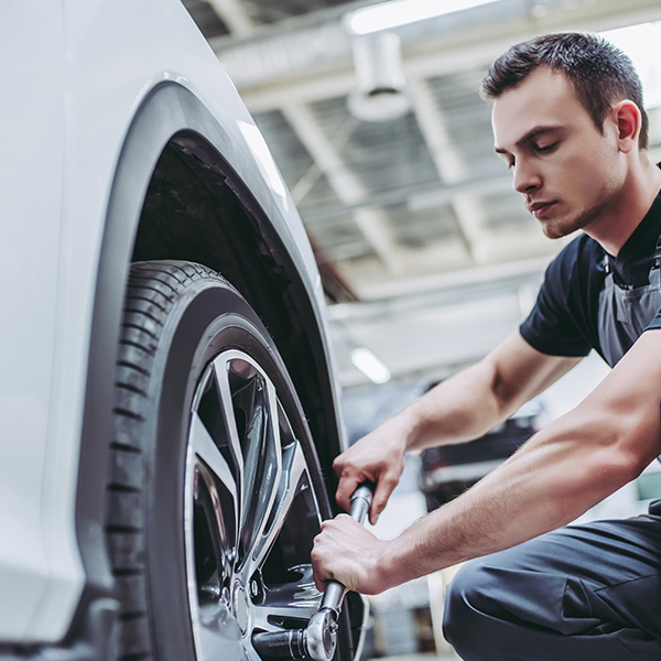 Mechanic changing car wheel inside auto shop in the New Port Richey and Port Richey, FL area